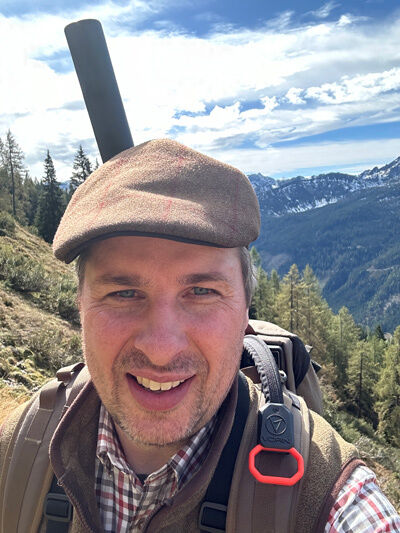 Alexander Busch in den Berge mit geschultertem VORN-EV30-Jagdrucksack und darin arretiertem Gewehr